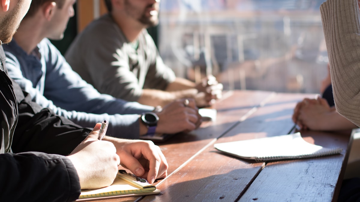Hands taking notes around a meeting table